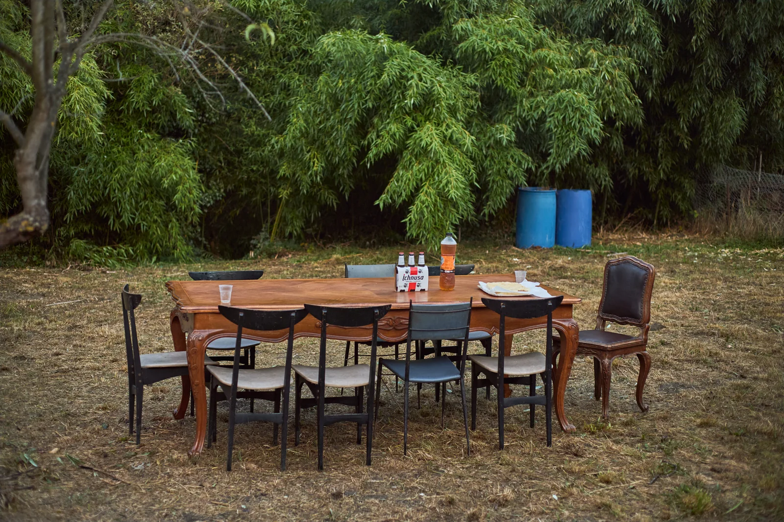 Wooden table and chairs outdoors, with glasses and bottles, without people.
