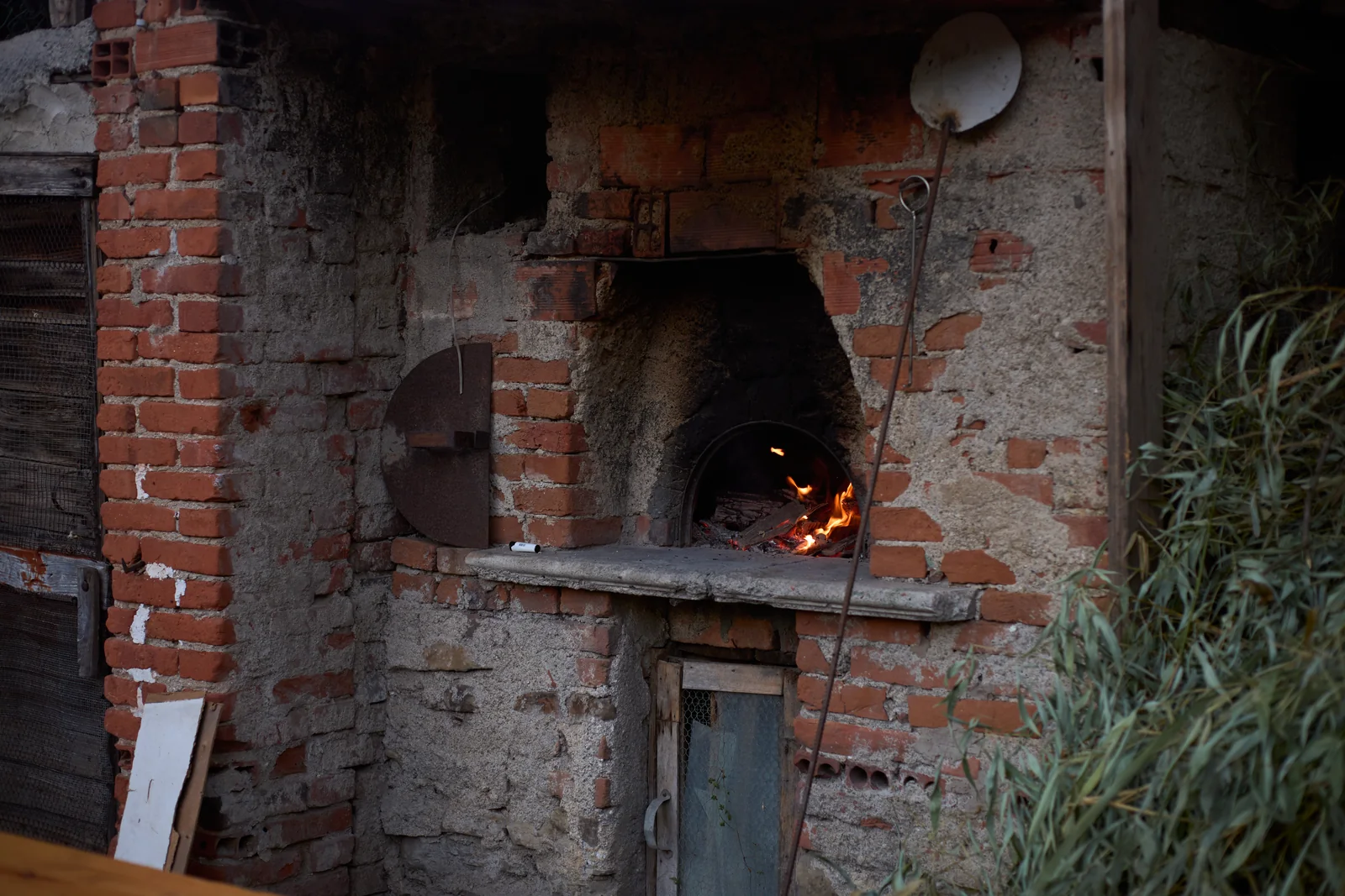 Rustic brick oven with a small fire burning.